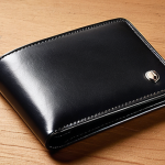 **Prompt:** A close-up studio shot of a Montblanc Meisterstück wallet, showcasing the full-grain European leather texture and the subtle Montblanc emblem. The wallet should have a slight patina, suggesting it's been gently used. Focus on capturing the high-quality stitching and smooth edges. Lighting should highlight the luxurious feel of the leather.