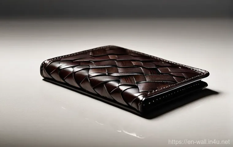 보테가 베네타 인트레치아토 지갑의 매력 - **Aesthetic of Everyday Elegance (Bifold Wallet):**
A close-up, high-angle, editorial photograph...